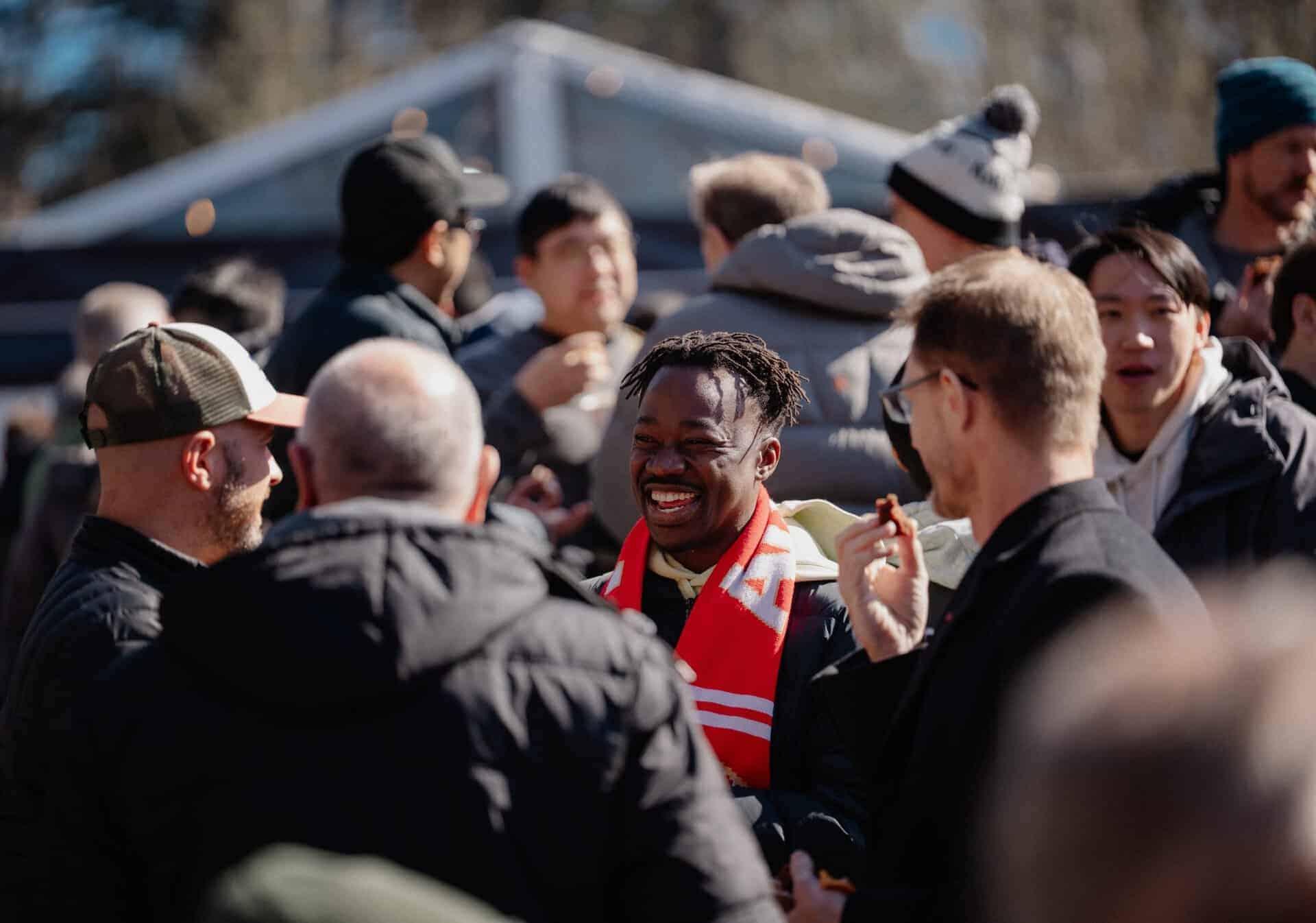 Group of diverse people smiling and engaging in conversation at Katoomba Christian Convention event, outdoor setting with tents in background.