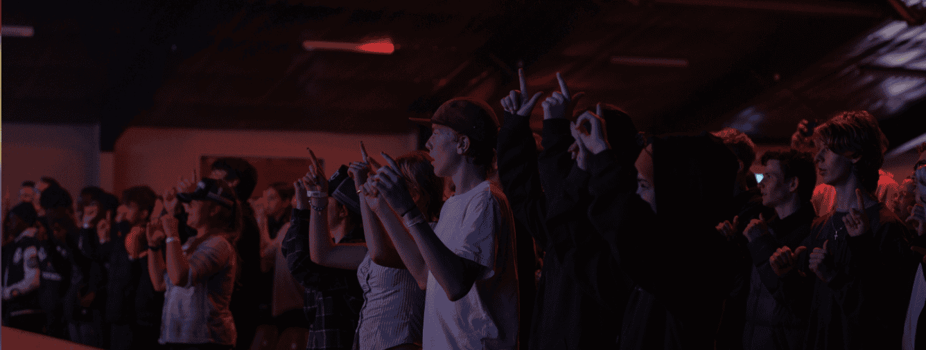 Group of young people engaged in worship at Katoomba Christian Convention, with hands raised in a dark, vibrant setting.