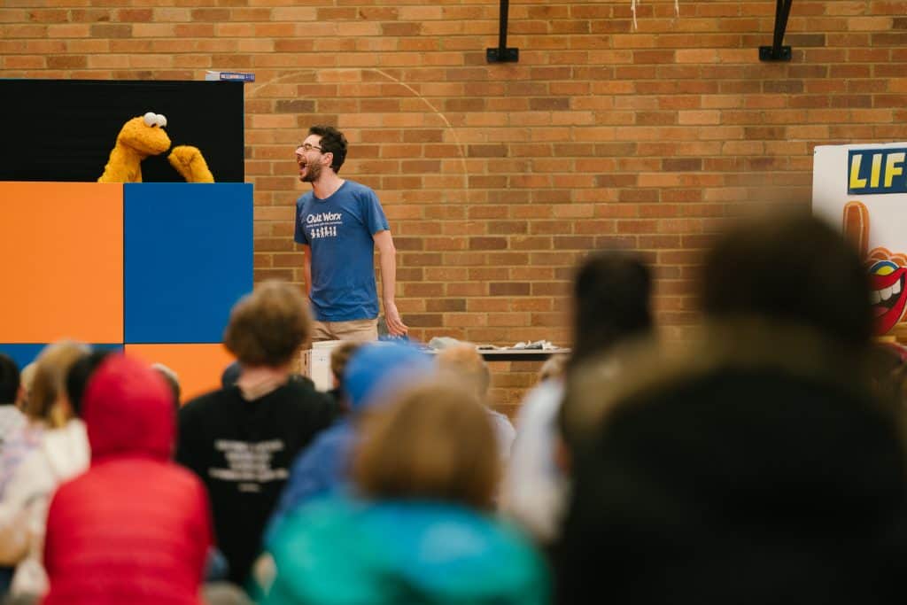 A speaker engaging an audience at KCC's "Fear Not" event during the Katoomba Christian Convention, with puppets and vibrant stage setup.