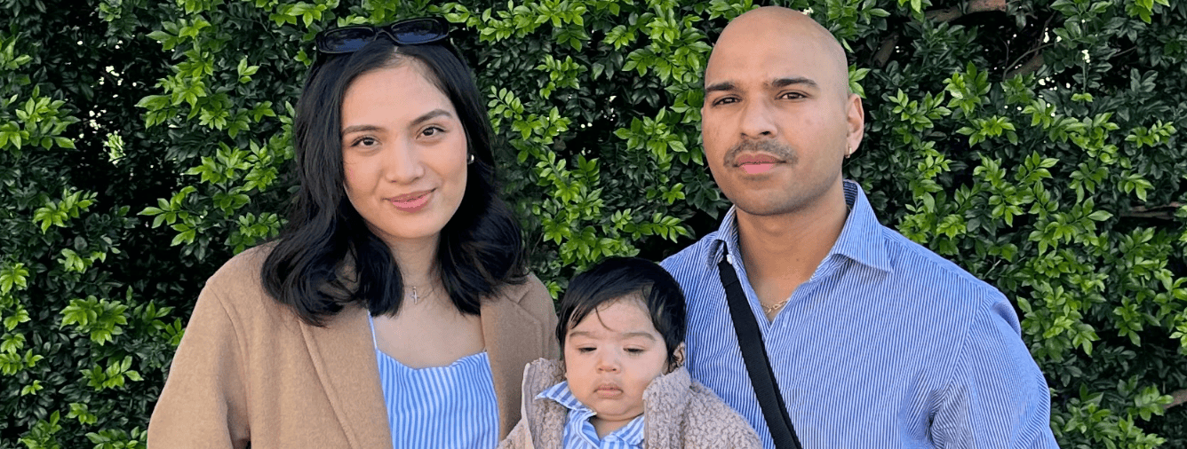 A family portrait of a mother, father, and their young child outdoors, highlighting themes of parenting and family life.