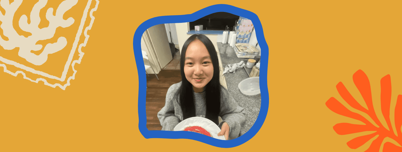 Young girl smiling at a youth event, holding a plate, in a casual setting.