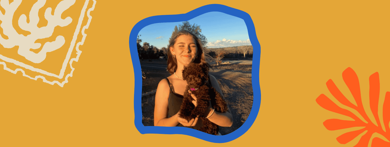 Young woman holding a small dog outdoors at Katoomba Christian Convention, smiling with scenic mountain views in the background.