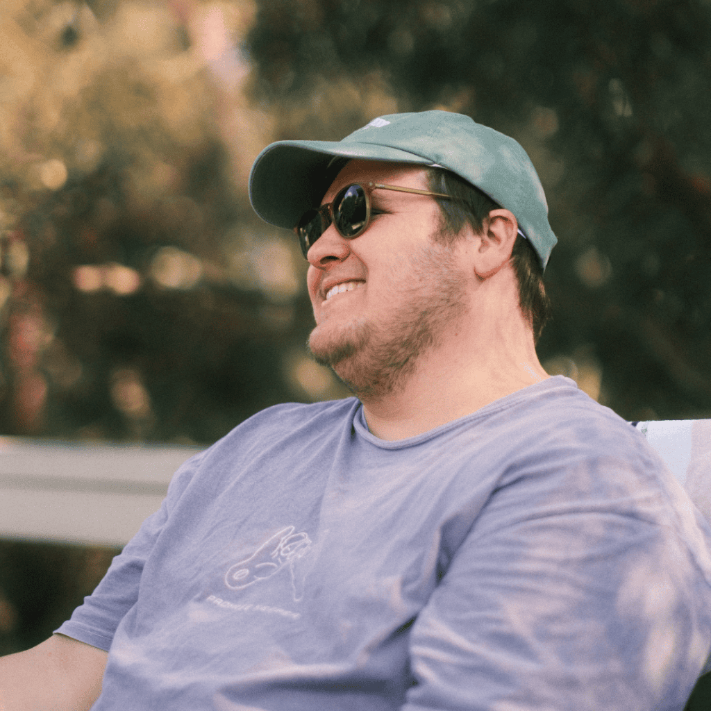 Smiling man wearing sunglasses and a cap enjoying outdoor event at KCC in Katoomba.