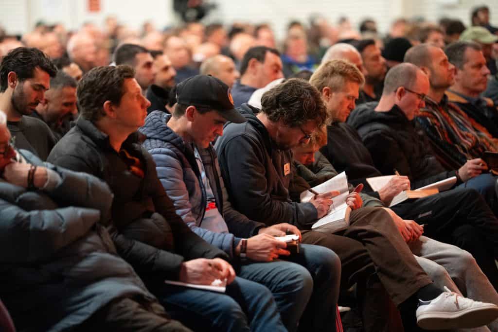Over 1,200 men attending the BASECAMP 2026 conference, seated in an auditorium, listening attentively to the speaker, representing a large Christian men's gathering.