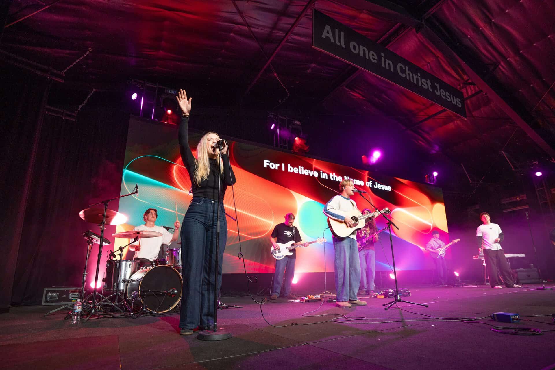 Live worship band performing on stage at Katoomba Christian Convention with vibrant lighting and a large screen displaying religious messages.
